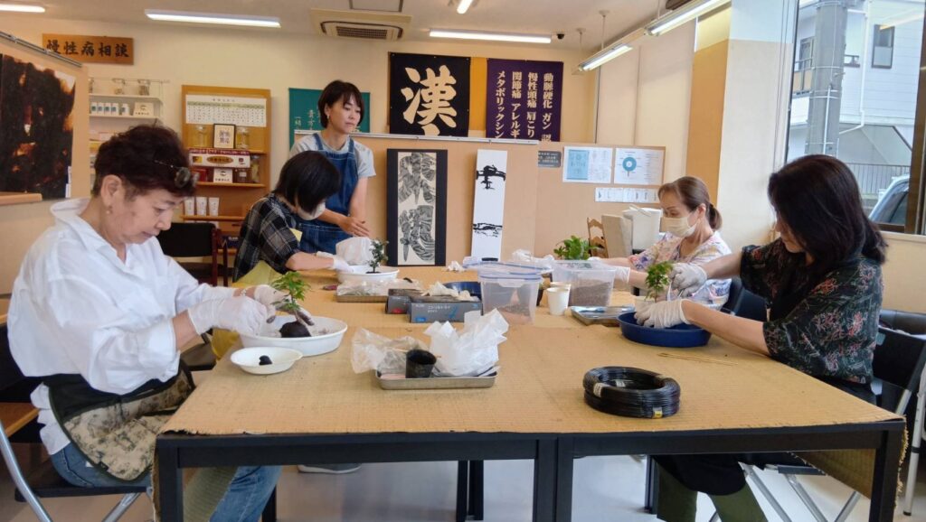 盆栽教室で参加者が作業する様子と、見守る講師