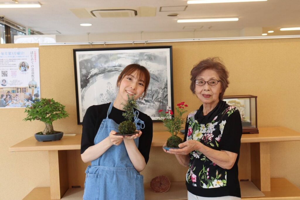 完成した作品を手にする参加者。右はミニバラ