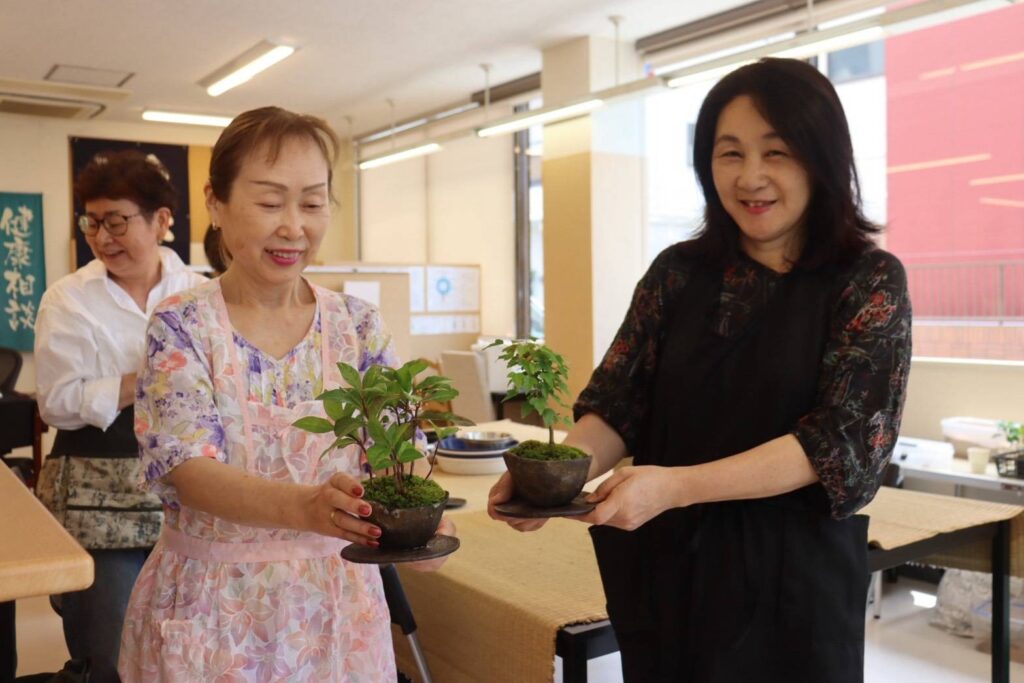 完成した作品を手にする参加者。左はヤブコウジ、右はカエデ